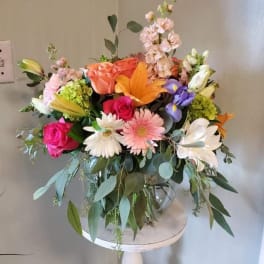 Colorful mixed bouquet in a clear glass vase on a white stand