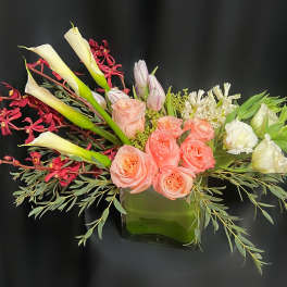 Pink roses and white calla lilies in a glass vase with red orchids