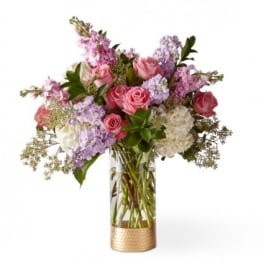 Pink and lavender roses arranged in a clear vase with white blooms