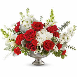 Red roses and white flowers arranged in a silver pedestal vase