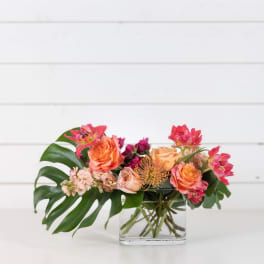 Mixed bouquet of orange and pink flowers in a clear glass vase