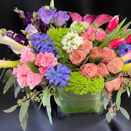 Colorful mixed flower arrangement in a square glass vase
