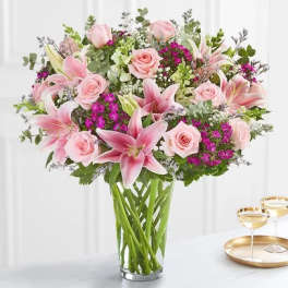 Pink lilies and roses arranged in a clear glass vase