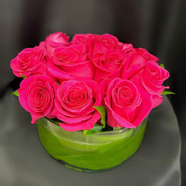 Bright pink roses arranged in a low round glass bowl