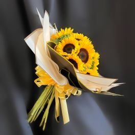 Bouquet of yellow sunflowers wrapped in cream and black paper with a yellow ribbon