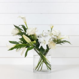 White lilies and roses arranged in a clear glass vase