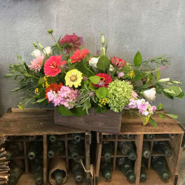 Mixed bouquet in a wooden box with pink, yellow, white, and green blooms
