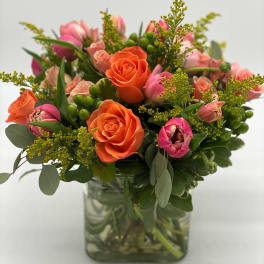 Orange roses and pink tulips in a clear glass vase