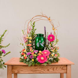 Floral arrangement with pink gerbera daisies around a green urn
