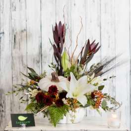 White lilies and dark burgundy flowers arranged in a white vase