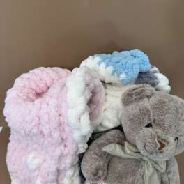 Plush teddy bear with pastel blankets in a box