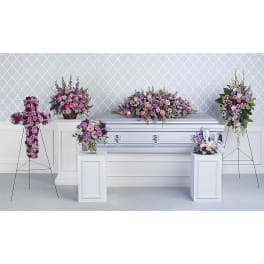 Funeral casket surrounded by pink and purple floral sprays