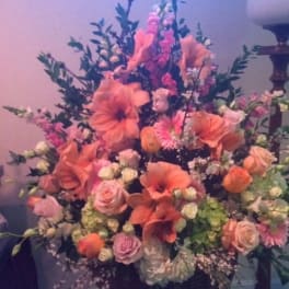 Large pink and peach floral arrangement in a dark vase