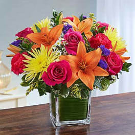 Bright mixed bouquet in a square glass vase