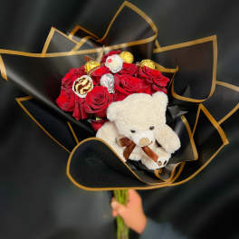 Red rose bouquet with chocolates and a teddy bear in black wrap