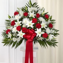 Standing floral spray with red and white flowers and a red ribbon