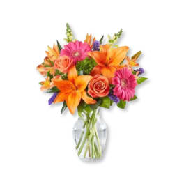 Bright mixed bouquet of orange lilies, pink gerberas, and roses in a glass vase