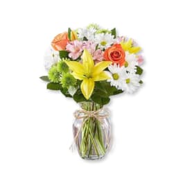 Mixed bouquet of roses, lilies, and daisies in a glass vase