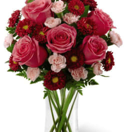 Pink roses and red daisies arranged in a clear glass vase