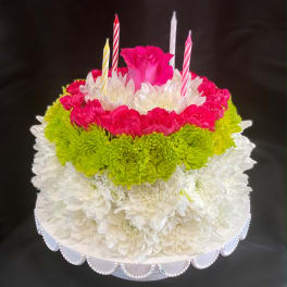 Round floral cake with pink, white, and green flowers and candles