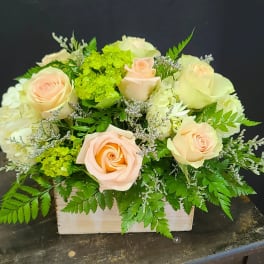 Peach roses and white hydrangeas in a wooden box