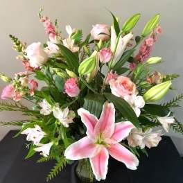 Pink lilies and roses arranged in a glass vase