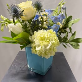 Blue and white floral arrangement in a square glass vase