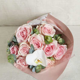 Bouquet of pink roses with a single white orchid wrapped in pink and clear paper