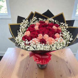 Bouquet of red and blush roses with white baby's breath in black wrap