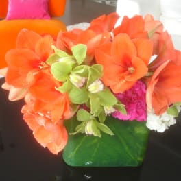 Orange and green floral arrangement in a green vase on a table