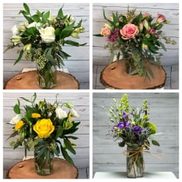 Four mixed flower bouquets in glass jars with pink, white, yellow, and purple blooms.