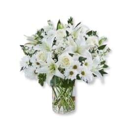 White lilies, roses, and daisies arranged in a clear glass vase