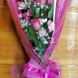 Pink rose bouquet wrapped in clear plastic with a bright ribbon