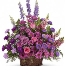 Purple and pink mixed flower arrangement in a wicker basket