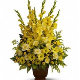 Tall yellow floral arrangement in a brown urn vase