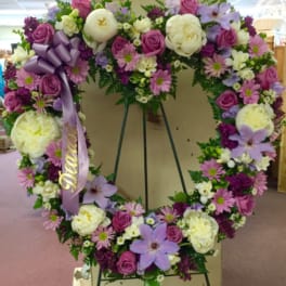 Heart-shaped floral wreath with pink, white, and lavender flowers on an easel