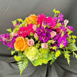 Bright mixed bouquet with orange roses, pink blooms, and purple flowers