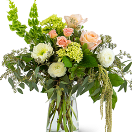 Mixed bouquet of peach and white flowers in a clear glass vase