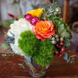 Colorful bouquet in a clear glass vase with roses, hydrangea, and greenery