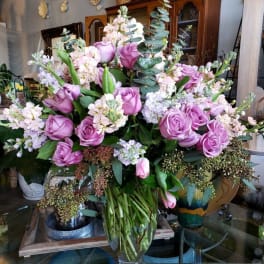 Lavender roses and pale pink flowers arranged in a clear glass vase