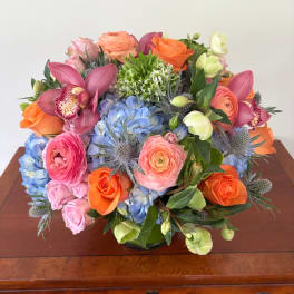 Mixed bouquet of roses, hydrangeas, orchids, and ranunculus in a low vase