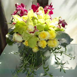 Bouquet of yellow roses and lime-green orchids in a glass vase