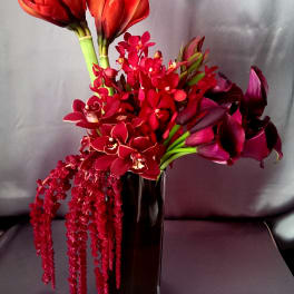 Red and purple flowers arranged in a tall glass vase
