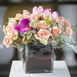 Pink roses and tulips arranged in a square glass vase