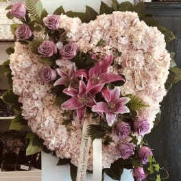 Heart-shaped floral arrangement with pink hydrangeas, purple roses, and lilies
