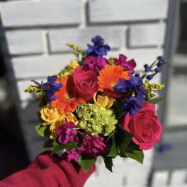 Handheld bouquet of bright mixed flowers with roses and gerberas