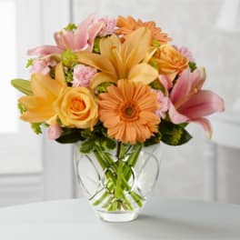 Bouquet of peach and pink flowers in a clear glass vase