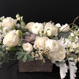 Cream floral arrangement in a wooden box with succulents and trailing greenery