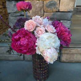 Pink and white peonies with small roses in a dark vase