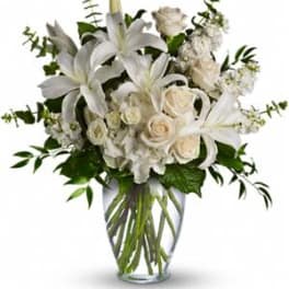 White lilies and roses arranged in a clear glass vase